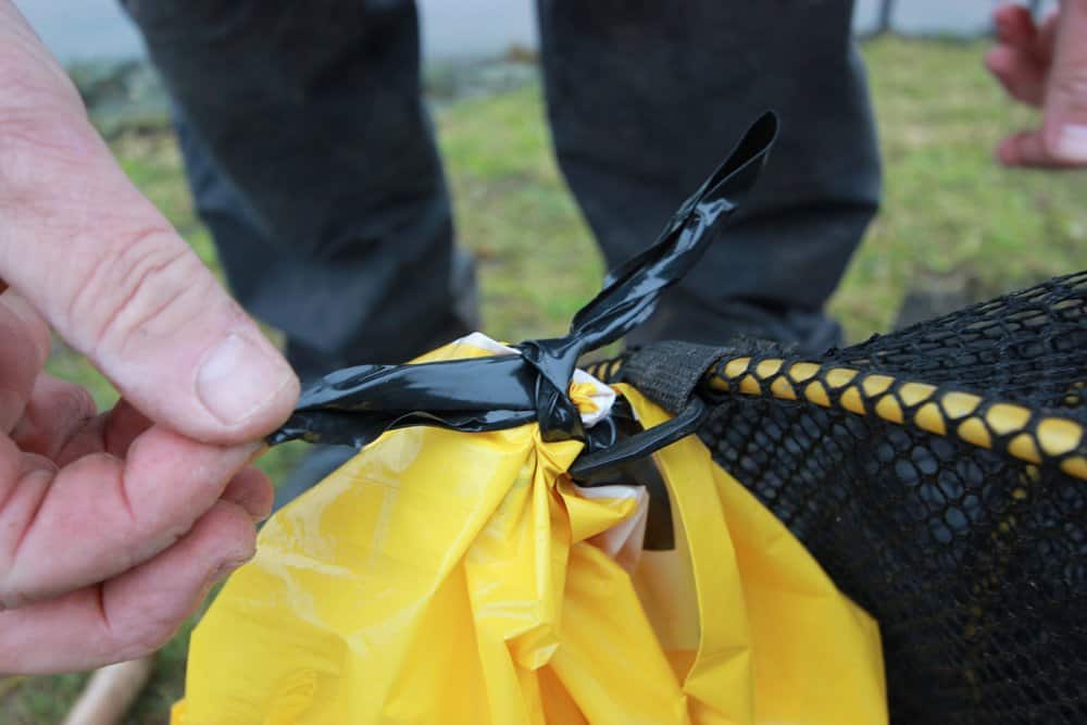 Na afloop van de vissessie trek je dan simpelweg de plastic zak kapot, waardoor de kapotte tas en het leefnet vrij komt...